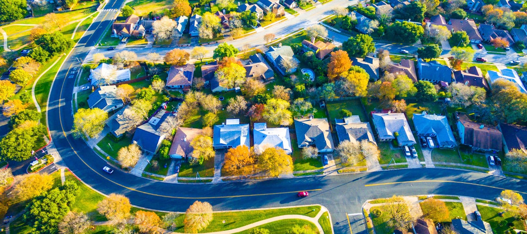Aerial view of a suburban neighborhood with colorful autumn trees